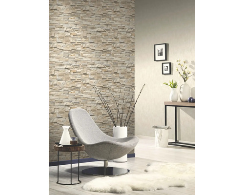 Obývacia izba s tapetou imitujúcou kameň, kreslom a dekoráciami pre útulnú atmosféru