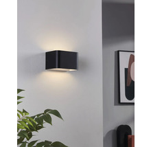 Čierne nástenné svietidlo v tvare kocky osvetľuje stenu