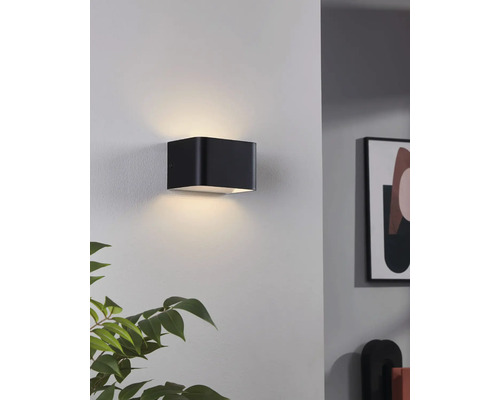 Čierne nástenné svietidlo v tvare kocky osvetľuje stenu