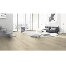 Svetlá obývacia izba s drevenou podlahou, schodiskom, sedením, okrúhlym kobercom a televízorom