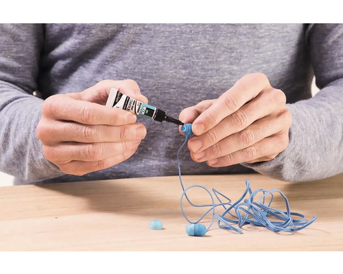 Osoba lepí slúchadlá sekundovým lepidlom.