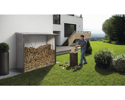 Sklad dreva s drevom vedľa muža rúbajúceho drevo v záhrade