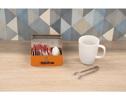 Kovová krabička na čaj s čajovými vrecúškami, šálka a kliešte na cukor
