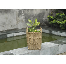 Dekoratívny ratanový kôš na rastliny s rastlinami na kamennej terase