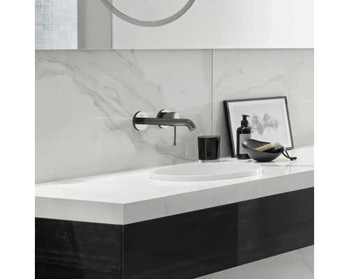 Moderná kúpeľňa s umývadlom, batériou, dávkovačom mydla a dekoratívnymi prvkami.