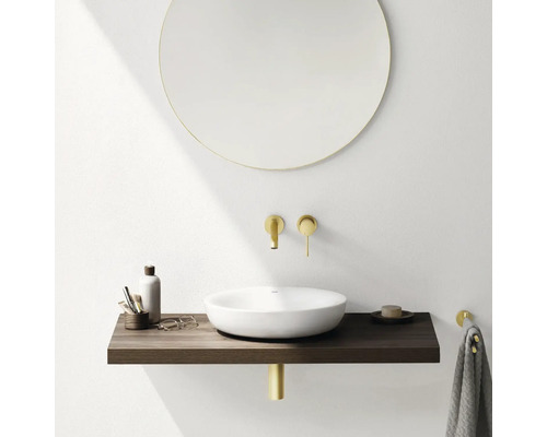 Moderná kúpeľňa s okrúhlym zrkadlom, umývadlom na dosku, drevenou konzolou a zlatými armatúrami.