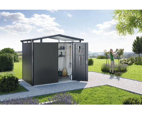 Záhradná búda s otvorenými dverami a ženou pracujúcou v záhrade