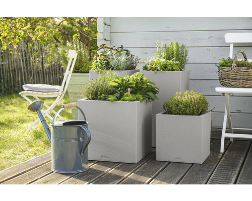 Tri štvorcové kvetináče s bylinkami a kanva v záhrade