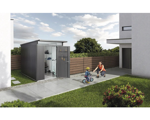 Moderný záhradný domček na náradie v záhrade s otvorenými dverami a hrajúcou sa rodinou.