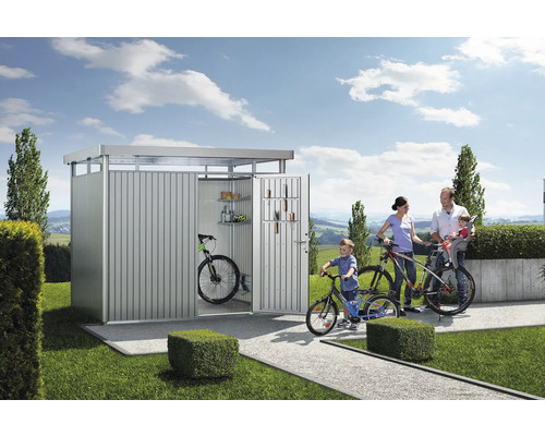 Rodina s bicyklami pred kovovou záhradnou búdou v záhrade.