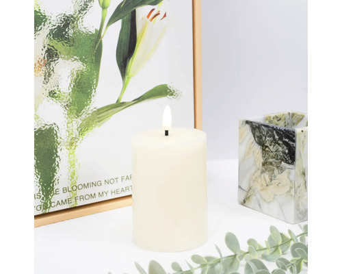 Dekoratívna LED stĺpová sviečka s maľbou v pozadí a mramorovaným svietnikom.