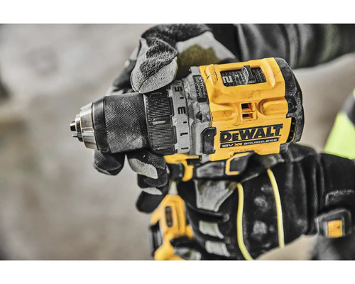 Detail akumulátorovej vŕtačky DeWalt v ruke remeselníka v pracovných rukaviciach