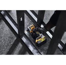 Logo spoločnosti DeWalt. Osoba skrutkuje kovový profil pomocou akumulátorového rázového uťahovača.