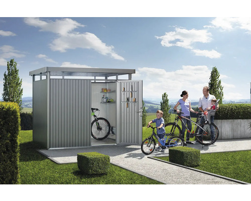 Rodina s bicyklami pred kôlňou na uskladnenie bicyklov a záhradného náradia.