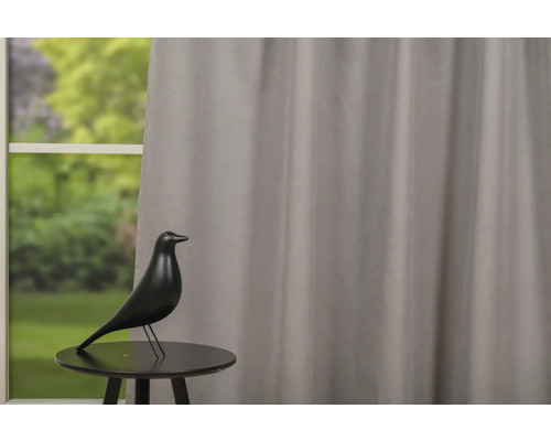 Dekorácia s vtákom na stole pred oknom so závesom