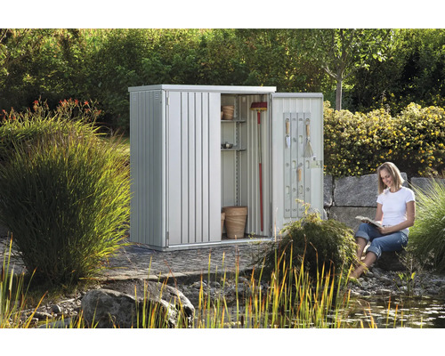 Kovová skriňa na náradie s otvorenými dverami a ženou čítajúcou v záhrade