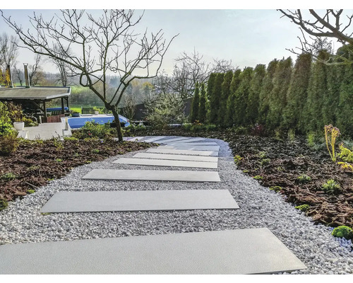 Záhradná scéna s chodníkovými doskami a štrkovou cestou medzi záhradnými rastlinami