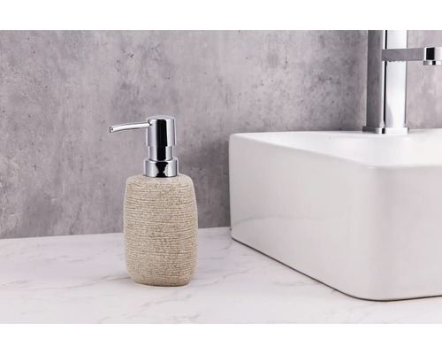 Dávkovač mydla so vzhľadom kameňa s chrómovanou pumpičkou vedľa umývadla