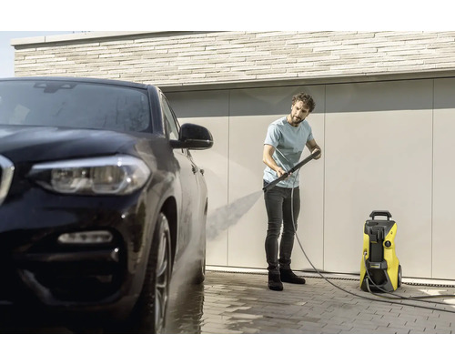 Muž čistí auto pomocou tlakovej umývačky.