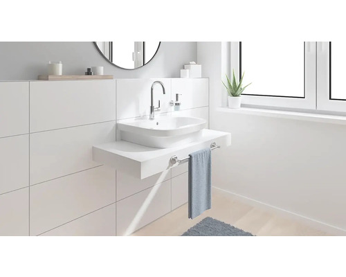 Moderná kúpeľňa s umývadlom na dosku, batériou a držiakom na uteráky pred bielou obkladanou stenou