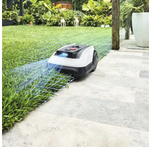 Robotická kosačka na trávniku a kamenných doskách v záhrade