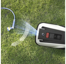 Pohľad zhora na robotickú kosačku a záhradnú hadicu na trávniku.