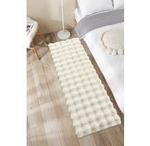 Chlpatý koberec v spálni vedľa postele a lampy.