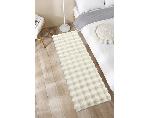 Chlpatý koberec v spálni vedľa postele a lampy.