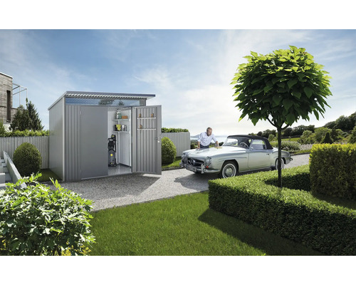 Záhradná scéna s domčekom na náradie, veteránom a mužom, ktorý sa stará o auto