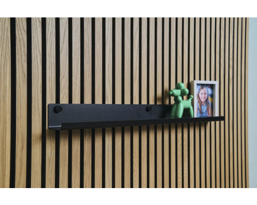 Čierna nástenná polica pred drevenou obkladovou stenou s dekoráciou