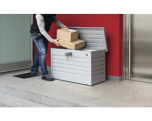 Doručovateľ vkladá balíky do kovovej schránky na balíky