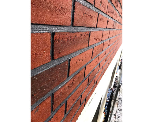 Detail fasády s červenými tehlami a sivými škárami