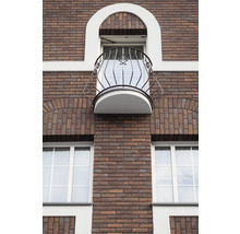Fasáda budovy s tehlovým murivom, oknami a balkónom