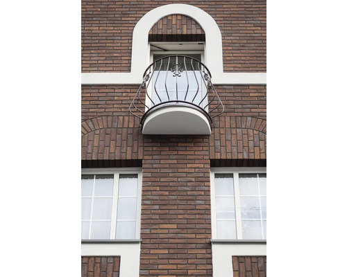 Fasáda budovy s tehlovým murivom, oknami a balkónom