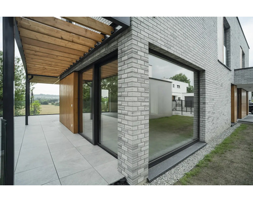 Vonkajší pohľad na dom s tehlovou stenou, terasou a pergolou