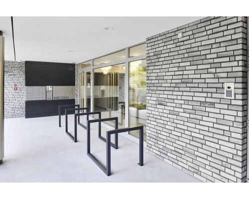 Vstupný priestor bytového domu s poštovými schránkami, stojanom na bicykle a tehlovou stenou