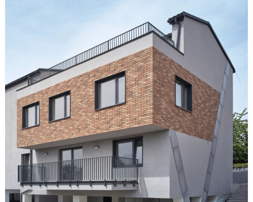 Moderná budova s tehlovou fasádou, oknami a balkónom