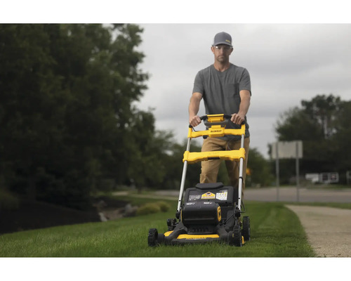 Muž obsluhuje žltú kosačku na trávu značky DeWalt v záhrade.