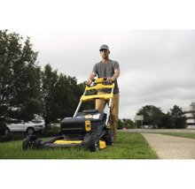 Muž tlačí žlto-čiernu kosačku na trávu v záhrade.