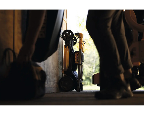 Zložený pracovný svetlomet DeWalt s transportnými kolieskami, uložený v dielni