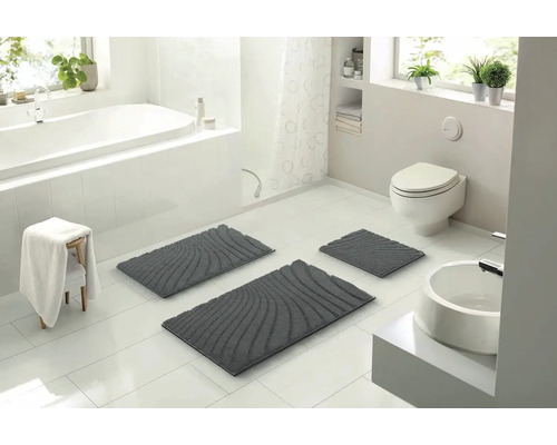 Svetlá kúpeľňa s vaňou, umývadlom, toaletou a súpravou troch sivých kúpeľňových koberčekov