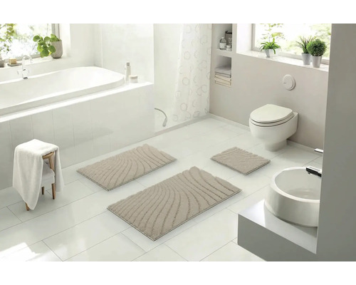 Svetlá kúpeľňa s vaňou, toaletou, umývadlom a súpravou béžových kúpeľňových predložiek so vzorom vĺn, pozostávajúcou z troch častí