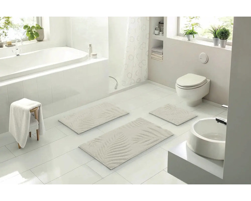 Svetlá kúpeľňa s vaňou, toaletou, umývadlom a súpravou kúpeľňových predložiek s palmovým vzorom