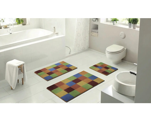 Moderná kúpeľňa s vaňou, toaletou, umývadlom a súpravou troch farebných kúpeľňových koberčekov