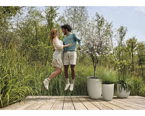 Scéna s párom na drevenej terase vedľa štruktúrovaných kvetináčov a záhrady