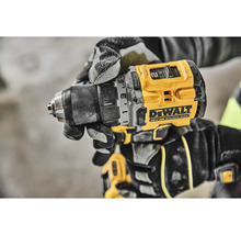 Akumulátorový vŕtací skrutkovač značky DeWalt v ruke s pracovnými rukavicami