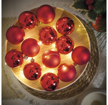Ozdobné červené vianočné gule so svetelnou reťazou na podnose