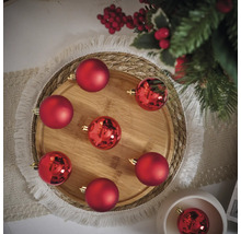 Dekoratívne usporiadanie červených vianočných gúľ na drevenej tácke