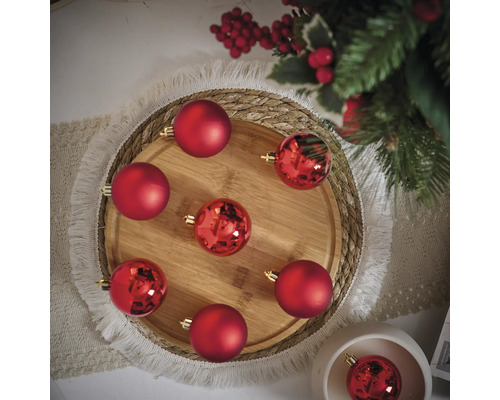 Dekoratívne usporiadanie červených vianočných gúľ na drevenej tácke