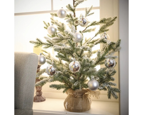 Malý vianočný stromček s ozdobnými guľami v jutovom vreci